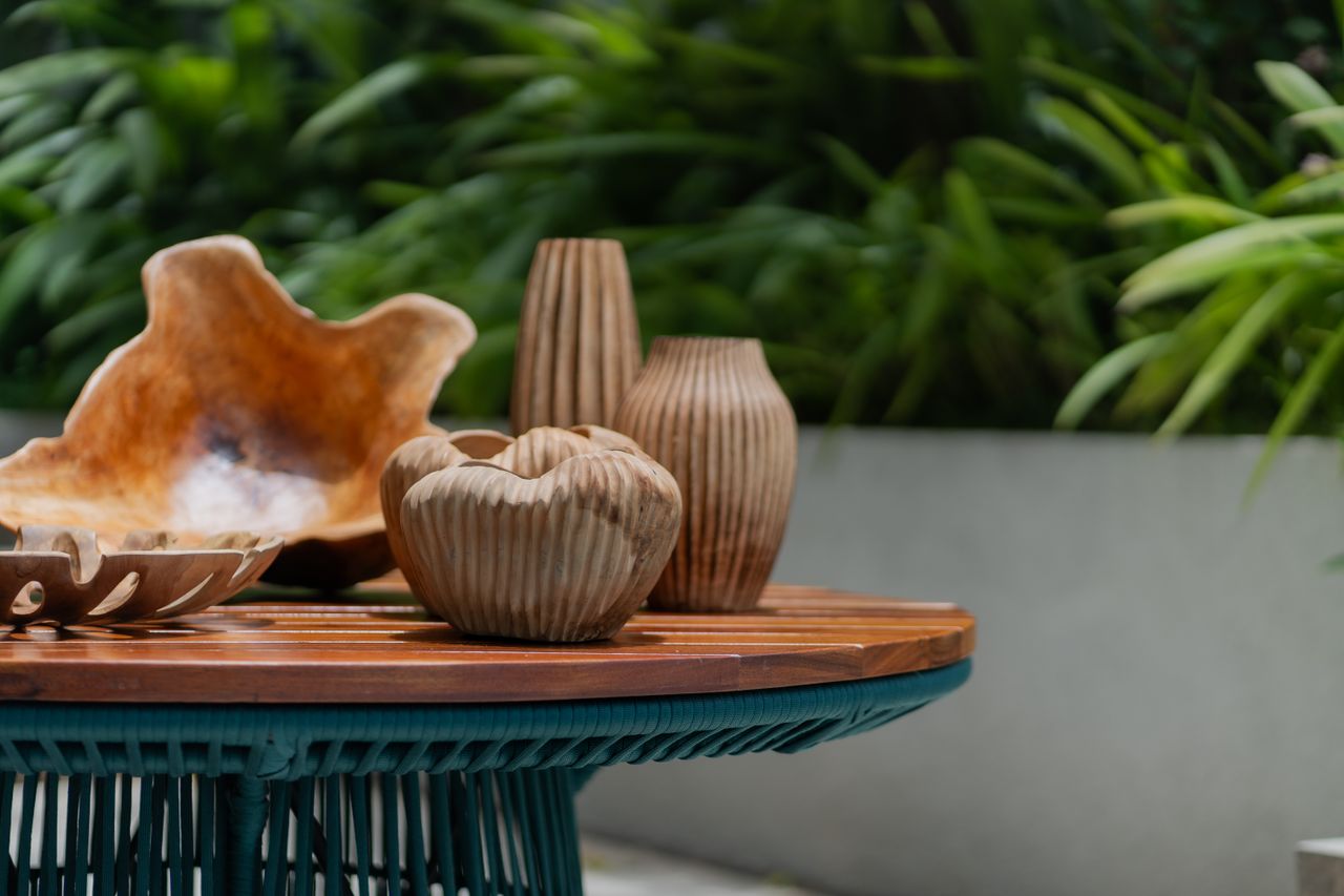 Sculptural wooden vessels against a leafy backdrop